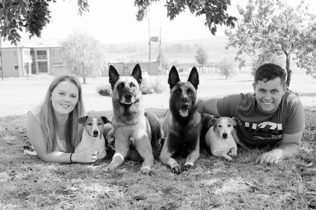 Greg and family lying in the grass with two Belgian Malinois and two Jack Russells